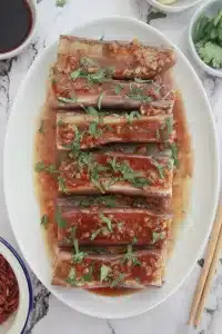 Vegan Sichuan eggplant with rich chili garlic sauce and chopped cilantro, presented on a marble background
