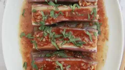 Vegan Sichuan eggplant with rich chili garlic sauce and chopped cilantro, presented on a marble background