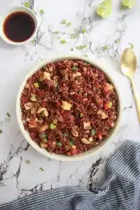 Protein-packed vegan fried rice with colorful vegetables, toasted cashews, and marinated tofu, garnished with spring onions