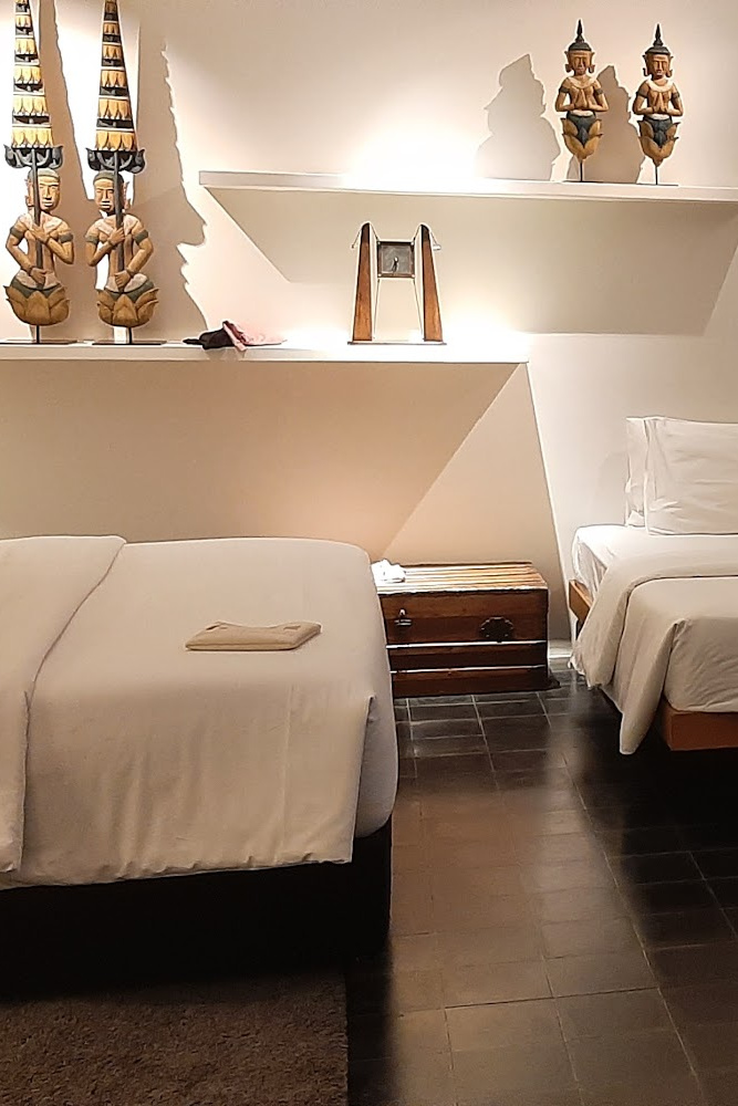 Elegant room at Viroths Hotel with minimalist decor, twin beds, and traditional Khmer accents on display