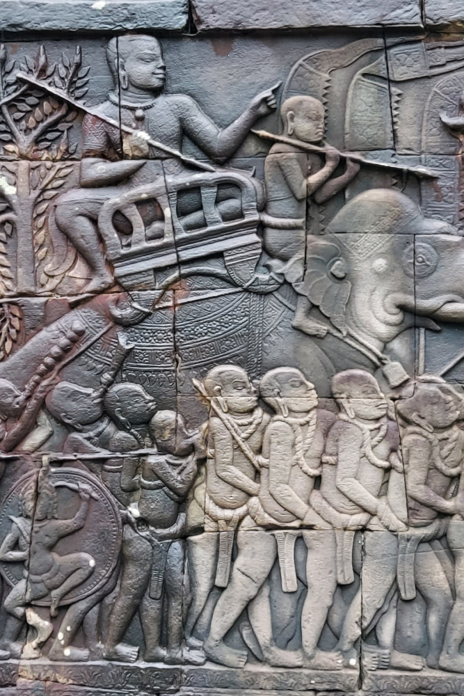 Intricate bas-relief carving at Bayon Temple in Angkor Thom, depicting historical scenes of warriors and elephants in Siem Reap, Cambodia