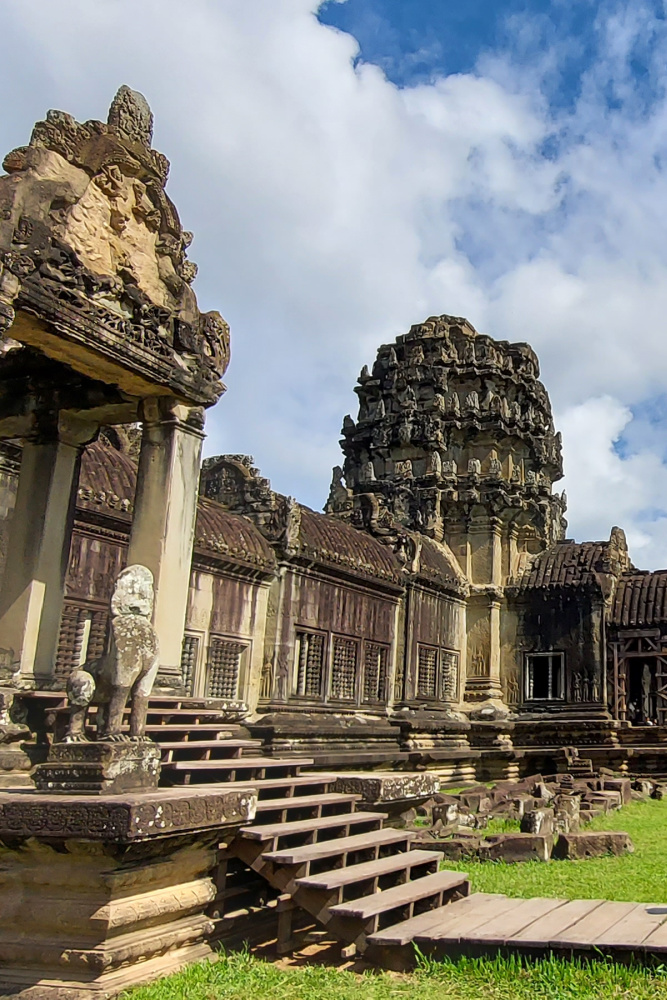 Intricate stone architecture of Angkor Wat temple in Siem Reap, showcasing carved details and historic stairways under a vibrant sky.