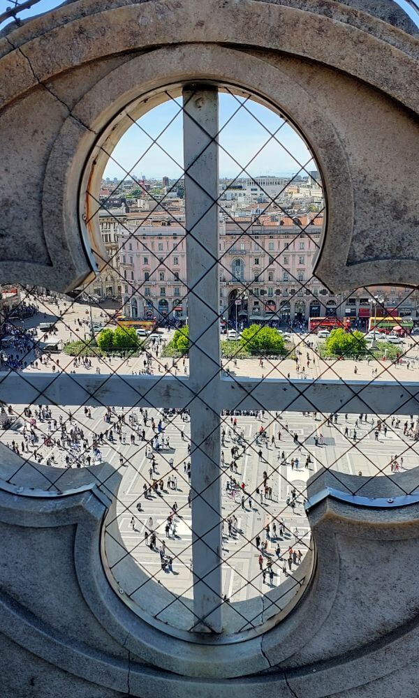 Looking down at Piazza del Duomo through a gothic window from the rooftop of Milan’s cathedral.