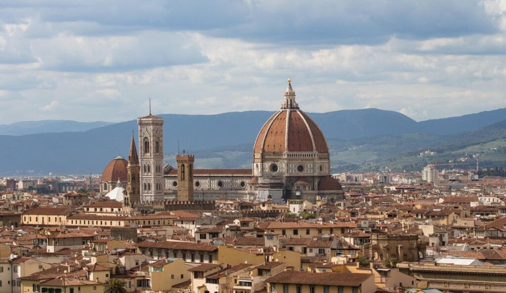 Distant view of Florence’s Duomo and terracotta rooftops framed by the Tuscan hills — a highlight of any 5-day Italy train itinerary.