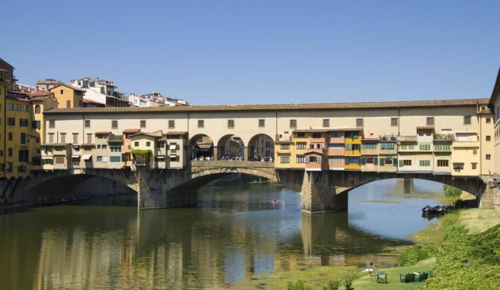 Florence’s Ponte Vecchio crossing the Arno River, with colorful buildings and calm water.