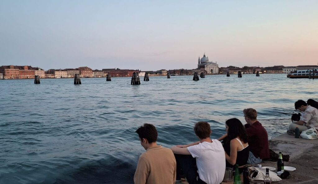 People sitting by the lagoon in Punta della Dogana, Venice, during sunset